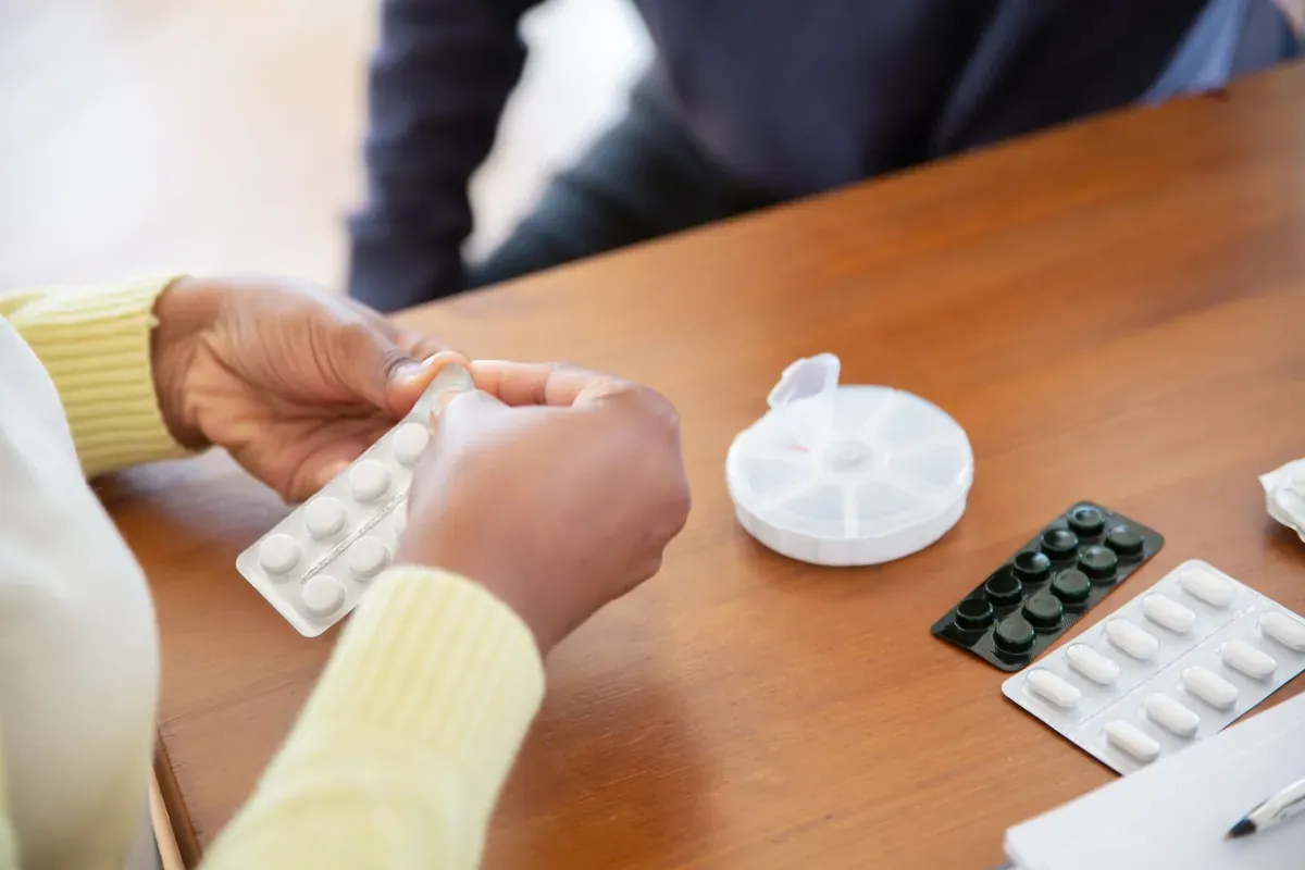 Hände, die Tabletten aus Blistern auf einem Tisch sortieren